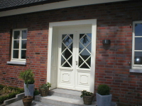 Haustür aus Holz mit Diagonalsprossen und Futterzarge mit profilierten Füllungen nach außen.